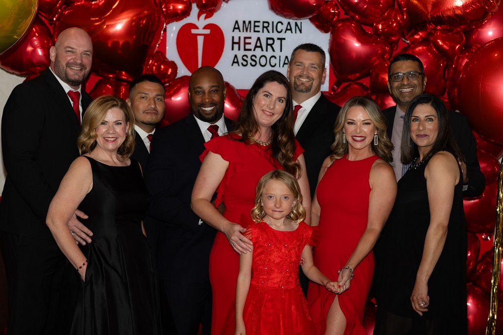 Nine guests and survivor child in front of American Heart Association sign